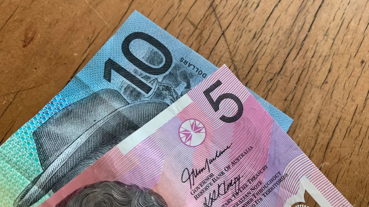 Australian five and ten dollar banknotes on a wooden desk, the real cost of studying in Australia