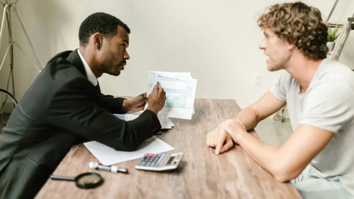 An adviser reviewing documents with a client across an office desk